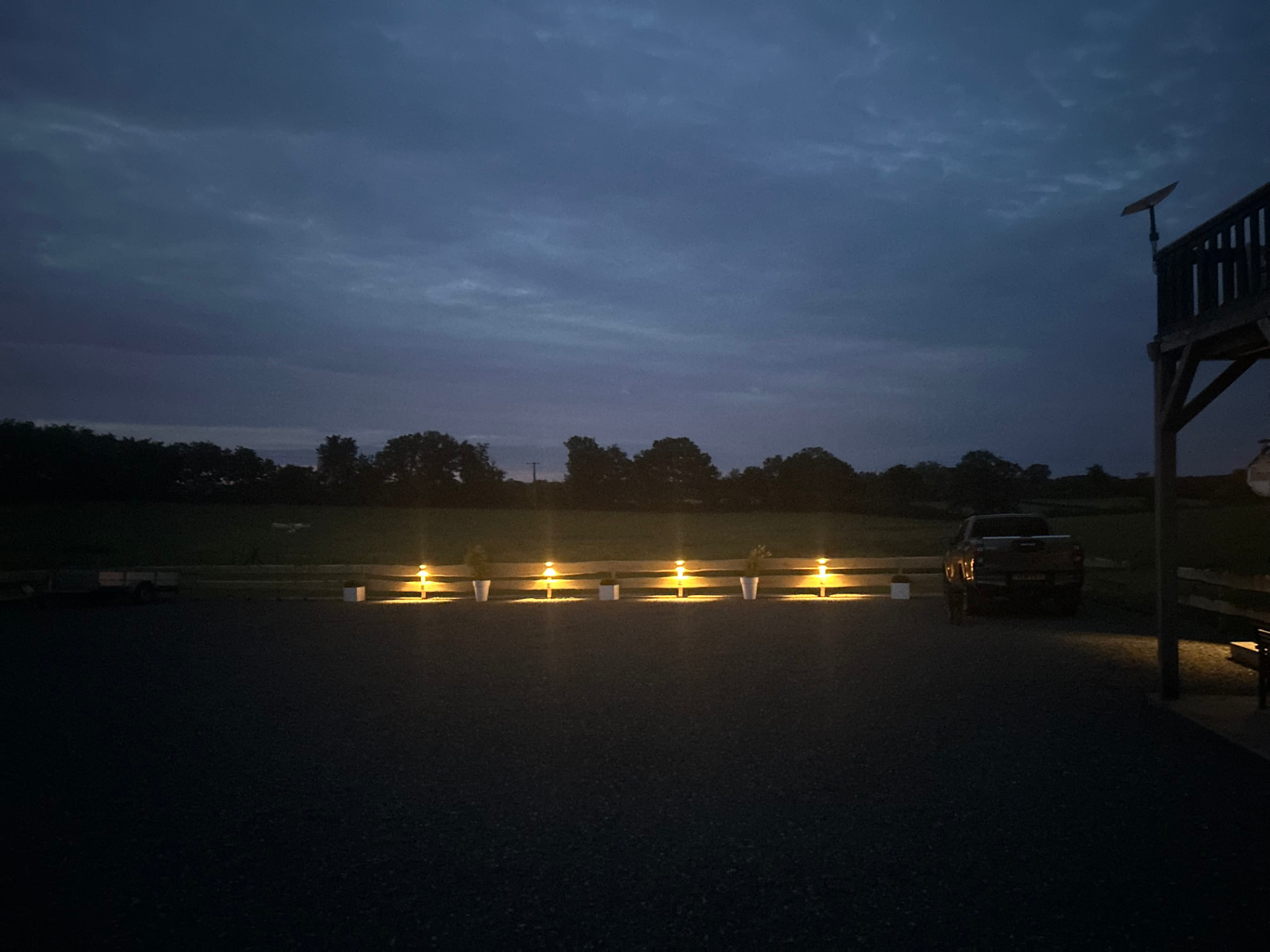 Het verlichte erf bij avond met zicht op de velden