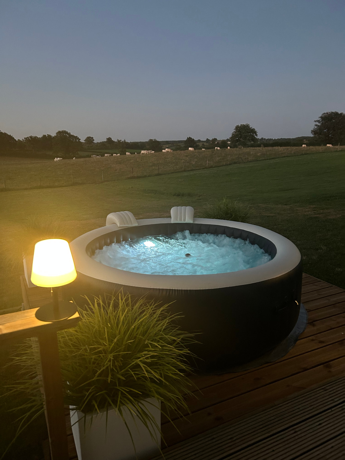 Verlichte jacuzzi bij schemering met uitzicht over de weides